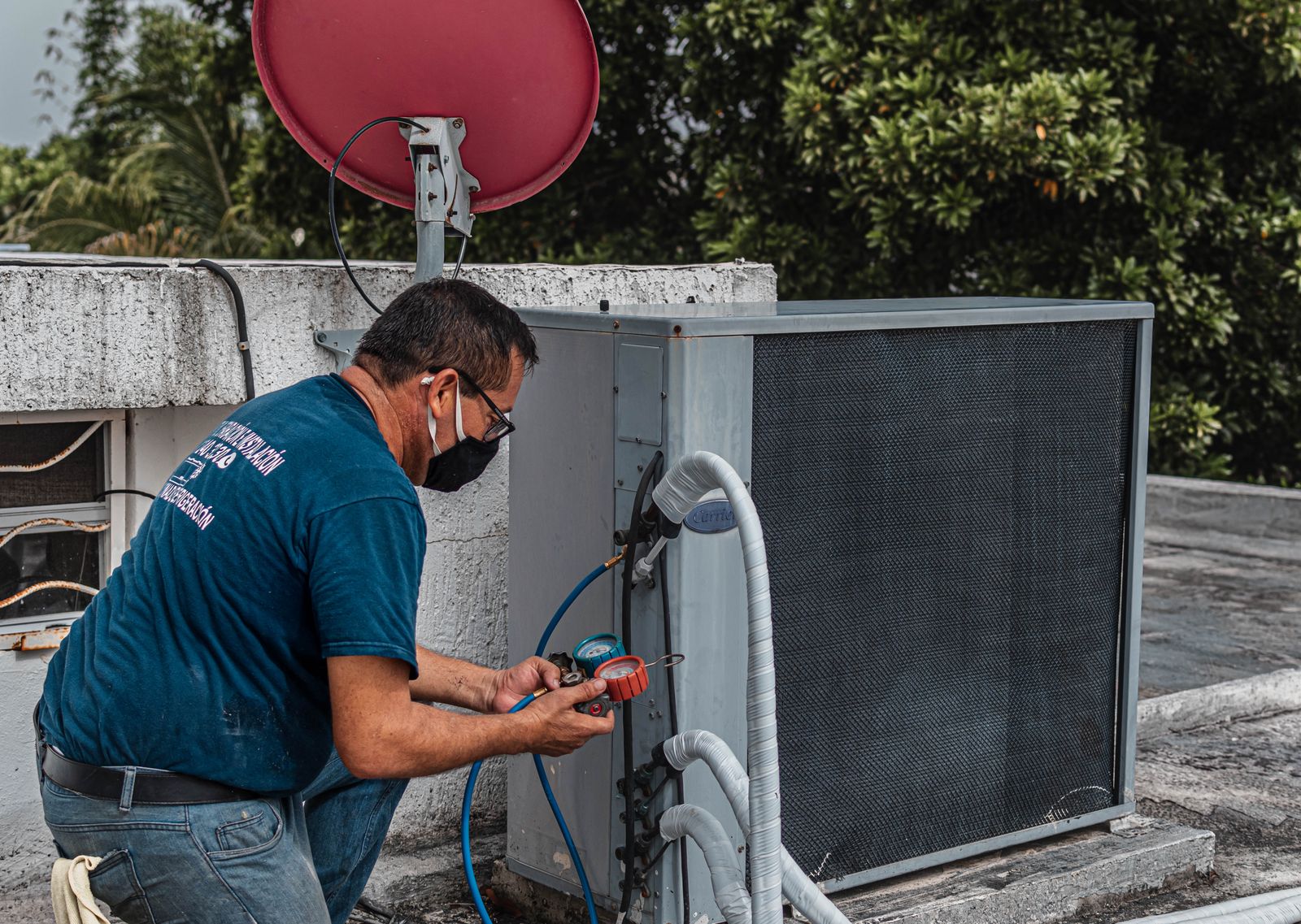 Technician repairing an outdoor air conditioner unit with a manifold gauge, by London HVAC Pros