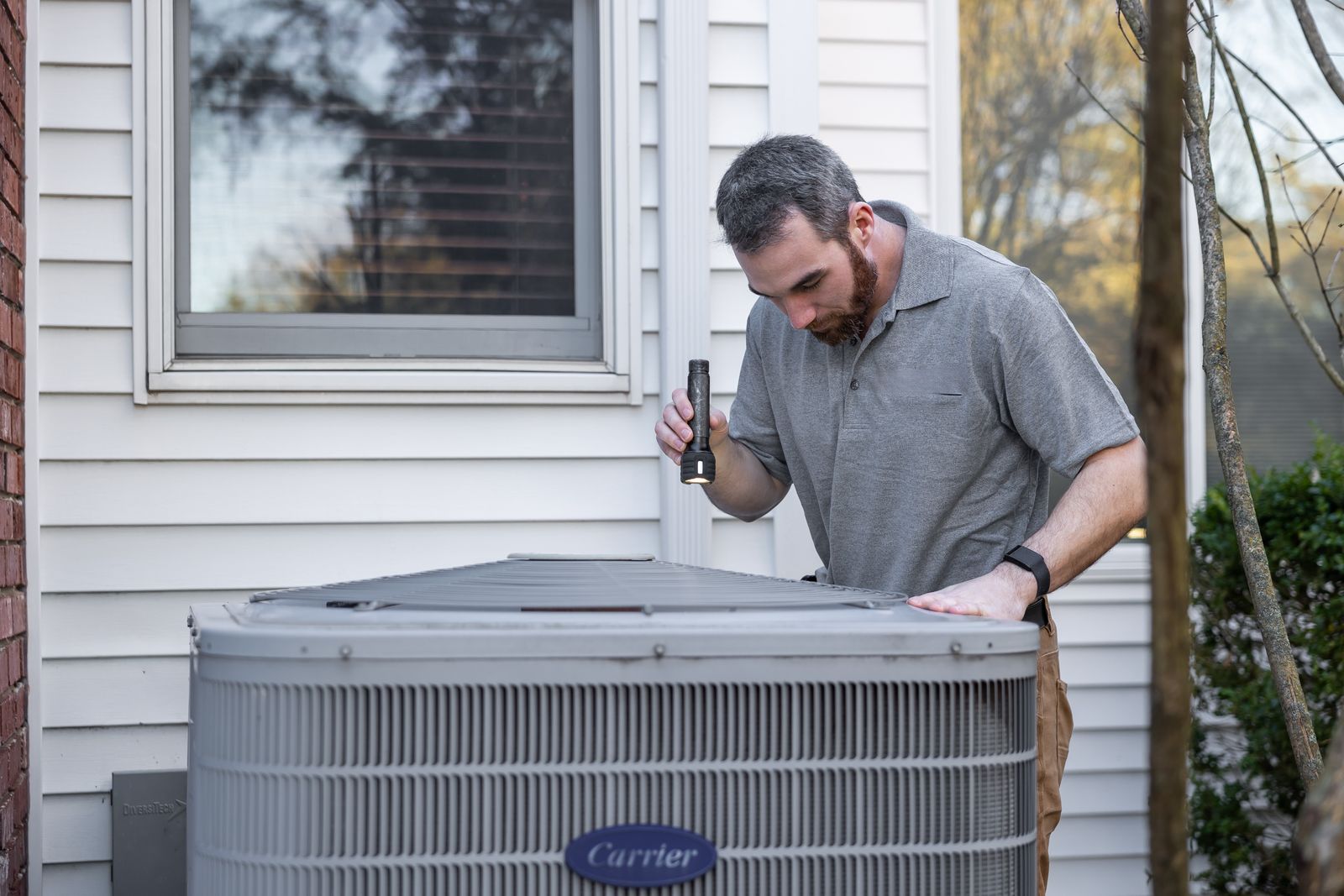 HVAC technician inspecting an outdoor air conditioning unit during a maintenance visit, by London HVAC Pros